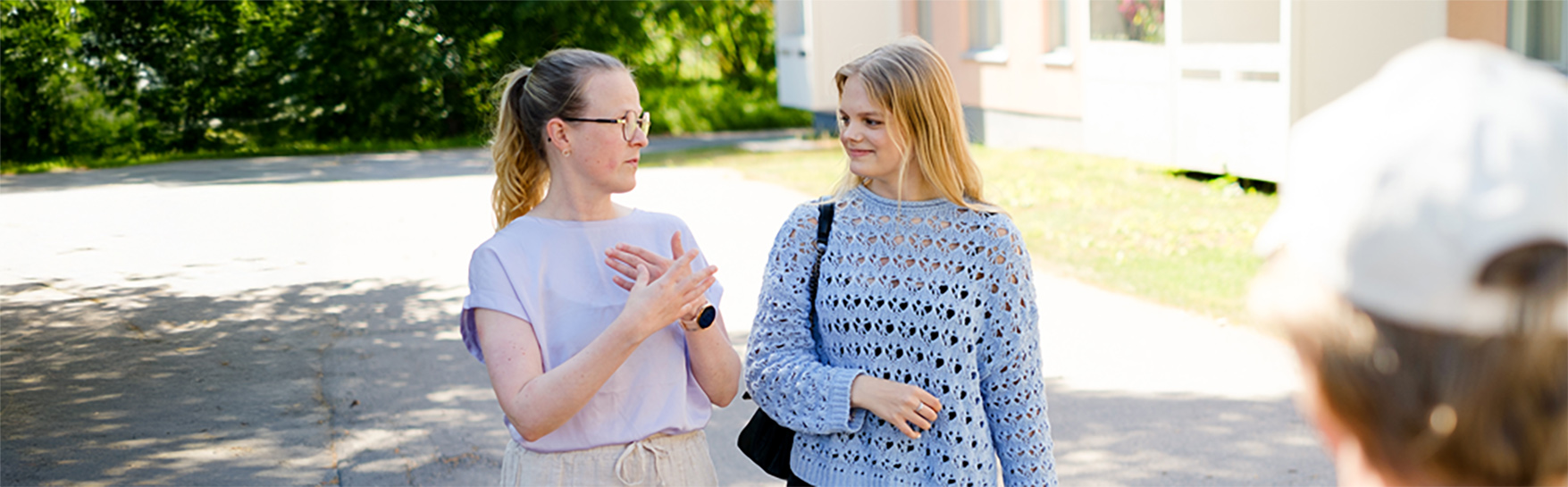 Kaksi naista keskustelee ulkona, toinen käyttää viittomakieltä. 